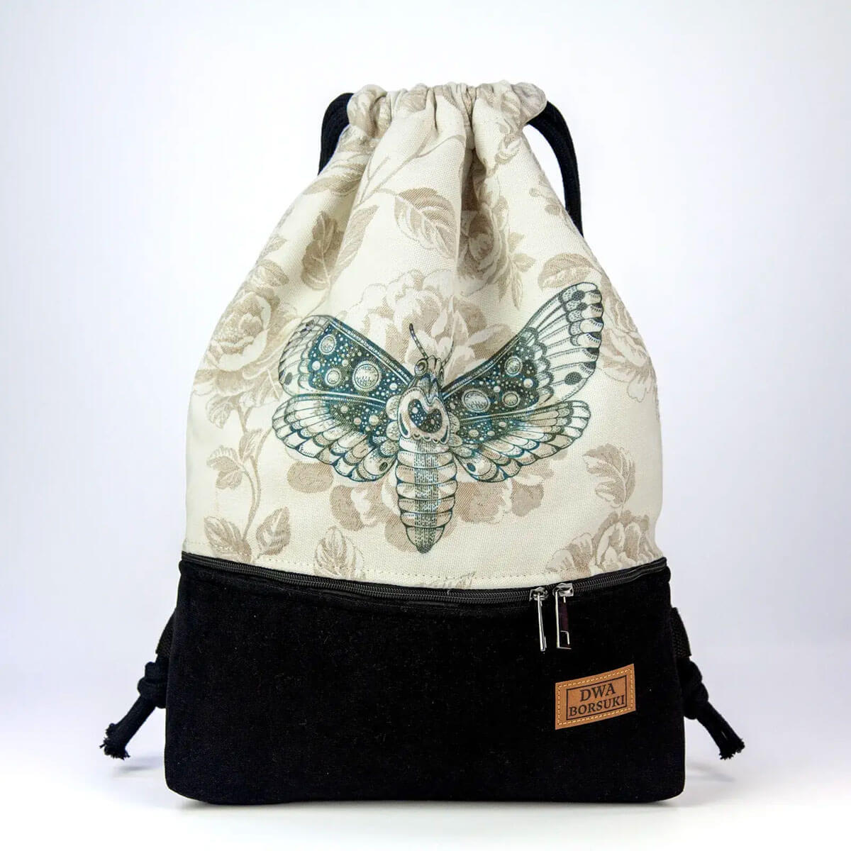 Przód workoplecaka z jasną żakardową górą w kwiaty, nadrukiem ćmy i czarnym welurowym dołem.